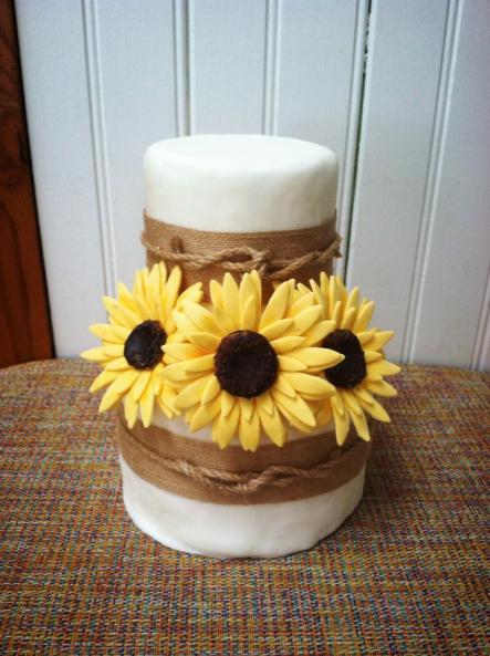A small two-tier rustic wedding cake with sunflowers